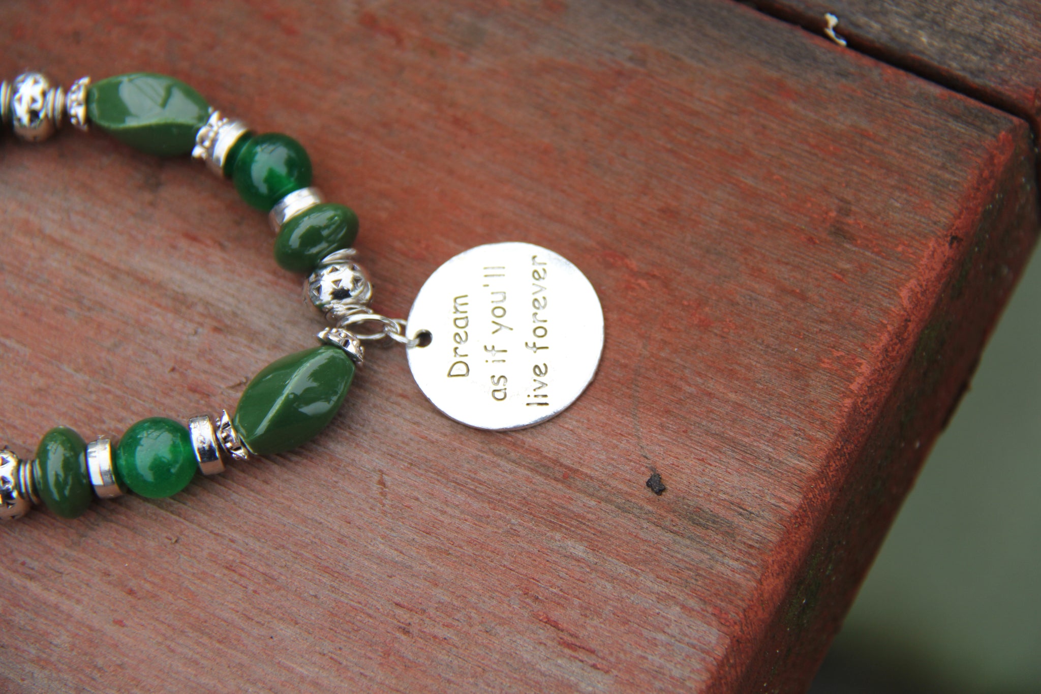 Green beads bottle bracelet with "Dream as if you'll live for ever" charm.